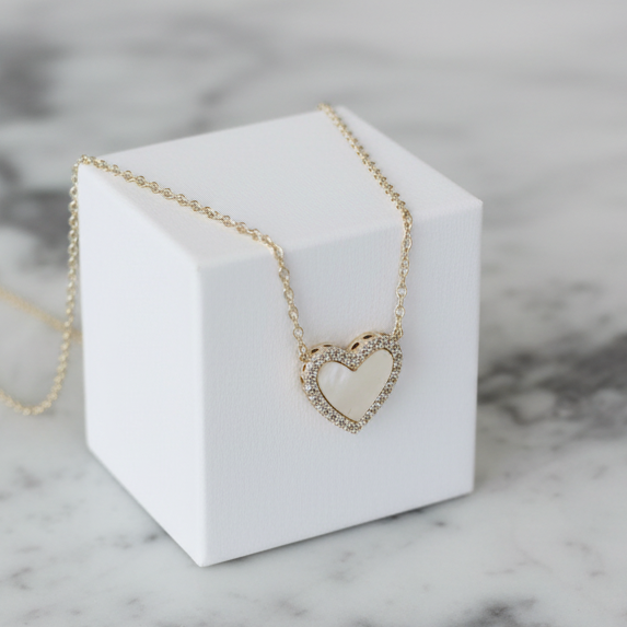 Dainty gold necklace featuring a white mother-of-pearl heart pendant by Lorena, close-up of elegant jewelry design.