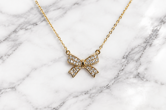 Gold CZ bow necklace from DX Collection, LLC featuring a delicate bow pendant on a fine chain.