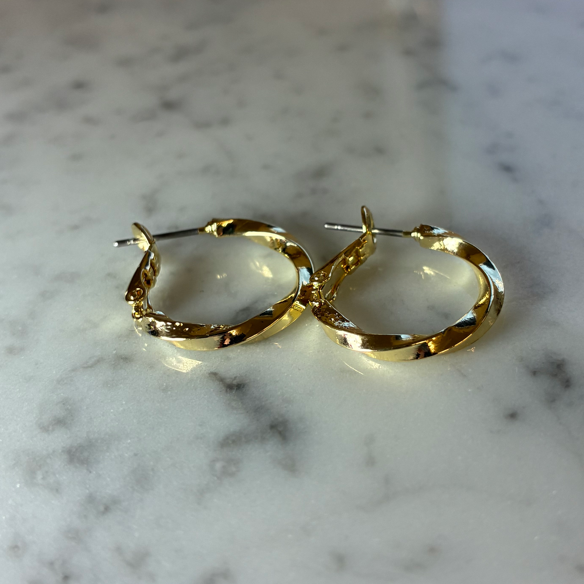 Small textured twist hoop earring by MX, showing a close-up of the silver hoop with detailed textured surface.