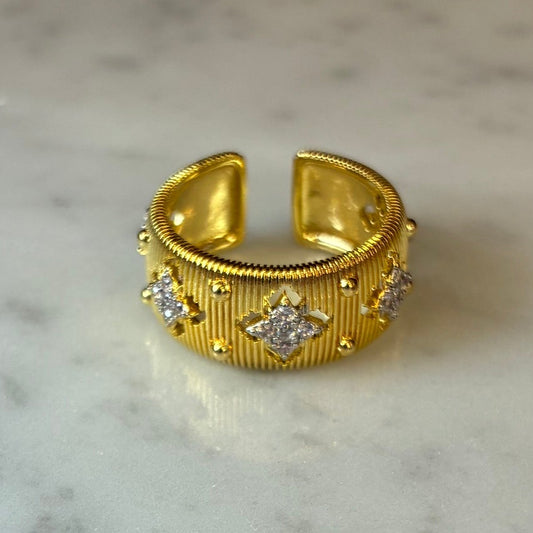 Adjustable matte gold flower ring with cubic zirconia from Joseph Anthony Inc., showing intricate flower design on a plain background.
