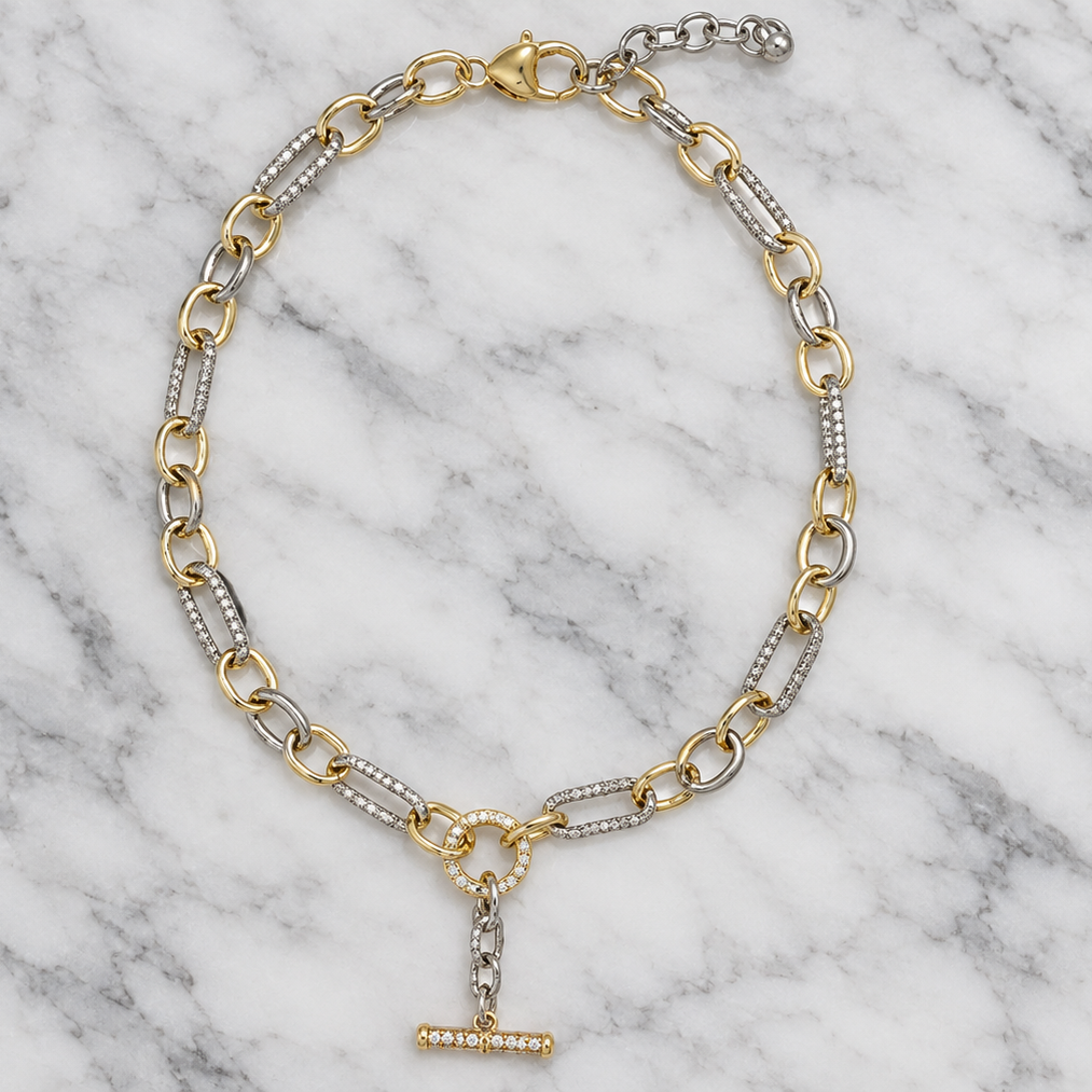MX two-tone cable link necklace with a dangle T-bar, featuring mixed-metal design on a marble background.