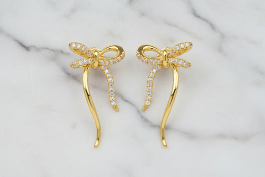 Gold CZ bow earring from DX Collection, LLC featuring a sparkling cubic zirconia bow design on a stylish earring.