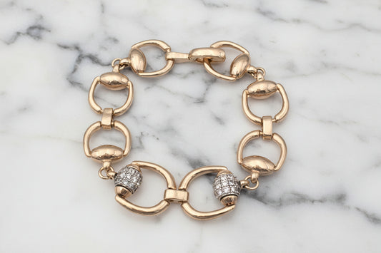 Lorena gold horseshoe link bracelet with pave barrel detail, showcasing intricate chain design and sparkling accents.