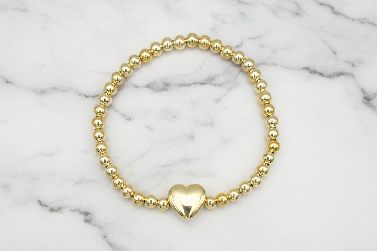 Gold beady stretch bracelet by Lorena featuring a heart charm, stylish and comfortable jewelry accessory.