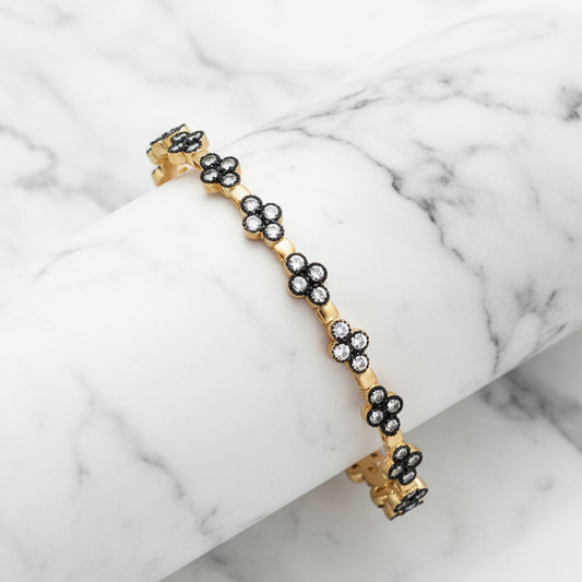 Gold hem CZ flower bangle bracelet by Lorena with sparkling flower design and CZ accents, stylish jewelry accessory.