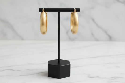 Lorena brushed gold oval hoop earrings hanging on display, showcasing their elegant, polished design.