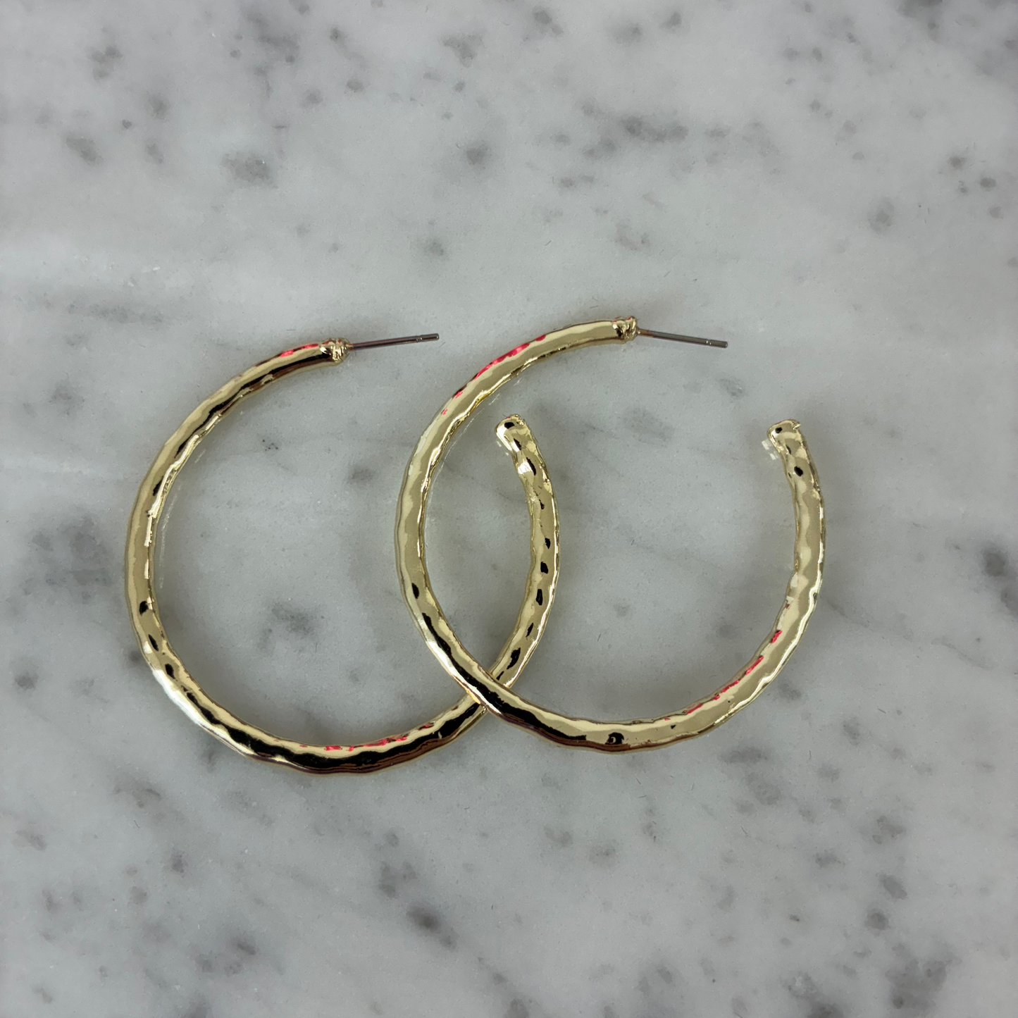 Lorena 1.5-inch shiny hammered hoop earring with a smooth, reflective surface and classic circular shape.