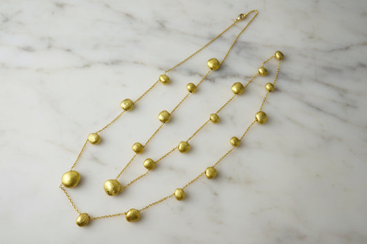 Lorena brushed gold bead necklace featuring smooth gold beads on a delicate chain, showcasing elegant jewelry design.