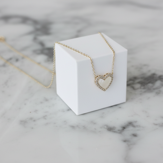 Dainty gold necklace featuring a white mother-of-pearl heart pendant by Lorena, close-up of elegant jewelry design.