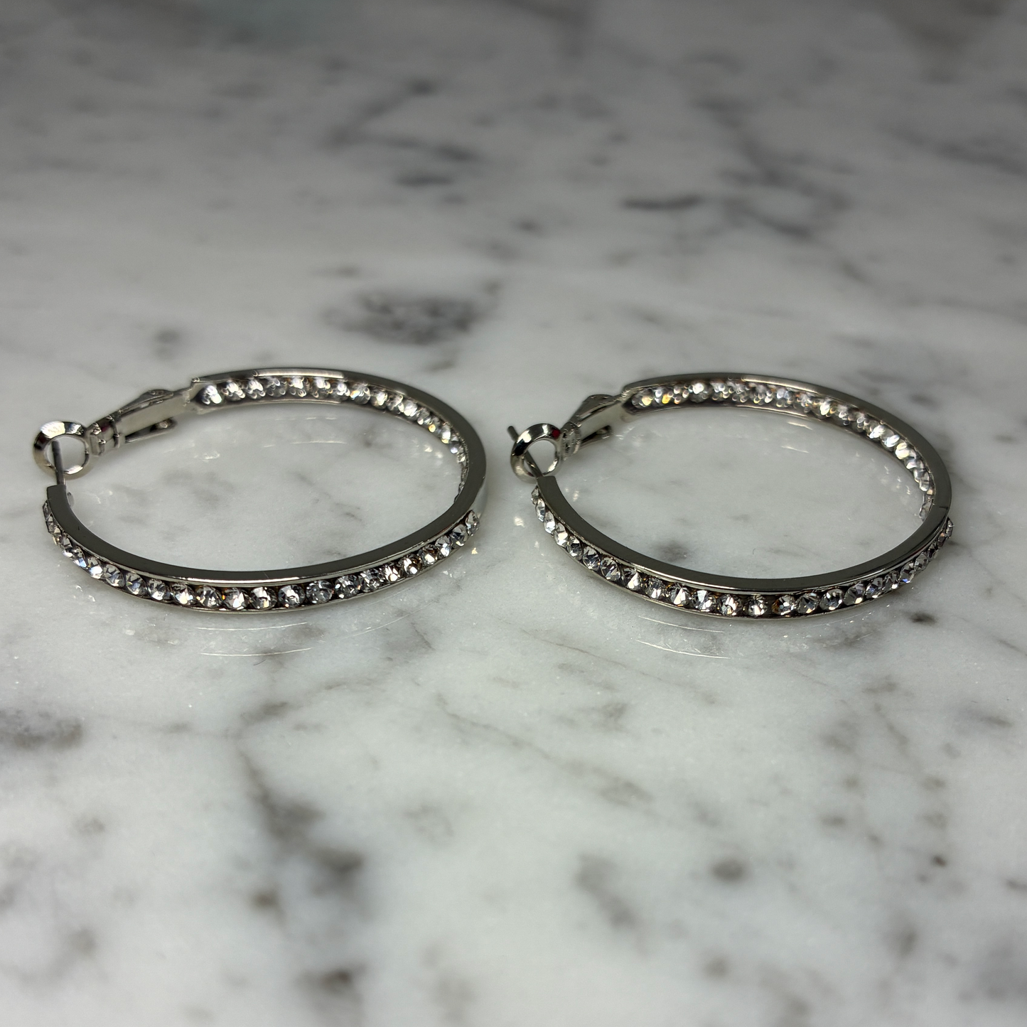 Silver hoop earring with sparkling cubic zirconia stones from Marcony, showcasing a sleek and elegant jewelry design.
